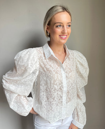 The Flora Top from Shop Silvs is a white button down puff sleeve top that adds a touch of elegance to any outfit. 