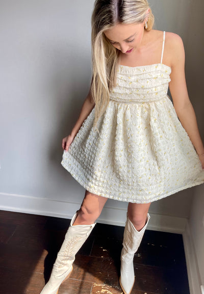 Pair this cream babydoll dress with ruffled bodice with cowboy boots for an adorable look.