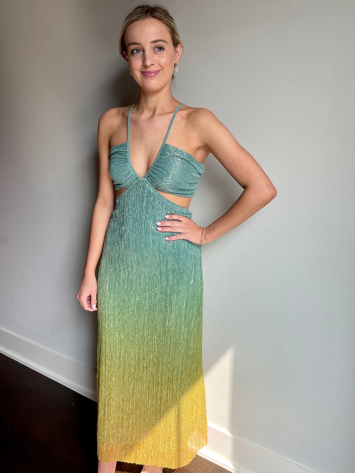 The Lucia Dress from Shop Silvs is a green and yellow beach dress featuring a ruched top, cut out sides, and bow tie detail in the back.