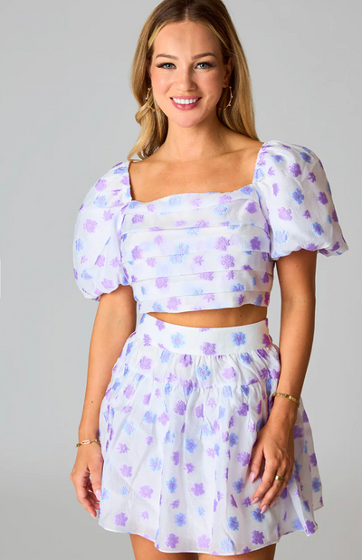 The BuddyLove Cutie Two-Piece Set sold by Shop Silvs is a blue, purple, and white puff sleeve mini skirt set by designer favorite BuddyLove.