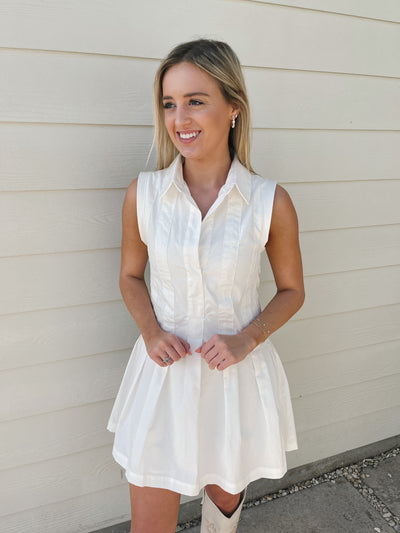 Pair this short white sleeveless dress with pleats with boots for a cute warm-weather look.